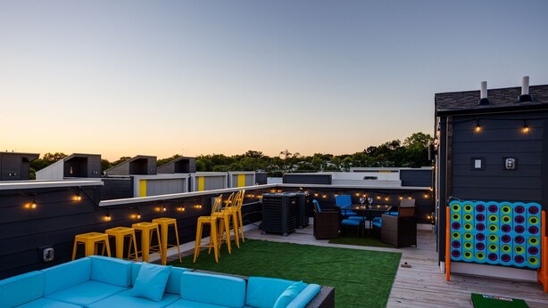 A rooftop patio with a blue sofa, yellow chairs, and a ping pong table. - Sweet Beat by ES ★ 4/4 ★ 13 Beds ★ Rooftop ★ HUGE (Nashville)