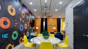 A modern dining area with a round table, yellow chairs, and a wall decorated with vinyl records. - Sweet Beat by ES ★ 4/4 ★ 13 Beds ★ Rooftop ★ HUGE (Nashville)