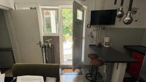 Cocina compacta con comedor, televisor sobre la encimera y un taburete pequeño.