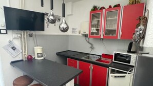 Una cocina compacta con encimera negra, armarios rojos y una cafetera.