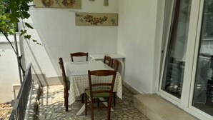 A dining area with a table and chairs, a tiled floor, and a window with a view. - Duga House Apartment A2 (Crikvenica)