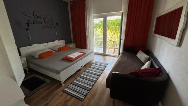 A bedroom with a bed, a sofa, a window, and a wall with a motivational quote. - Duga House Apartment A2 (Crikvenica)