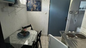 Een kleine keuken met een eettafel, stoelen en een fornuis.