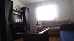 A living room with a sofa, a coffee table with wine glasses and a bottle, a TV, and a cabinet. - Apartments Marija Kruševo A2+2 (Kruševo)