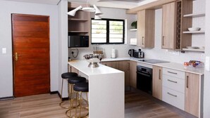 Une cuisine moderne dotée d’un îlot central, de meubles en bois et d’un plan de travail blanc.