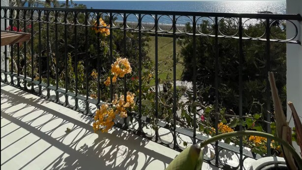 A balcony with a view of the sea, a palm tree, and yellow flowers. - La Petite For t Seaview Flat in Marbella (Estepona)