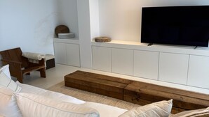 A modern living room with a white sofa, a wooden coffee table, and a flat-screen TV mounted on a white cabinet. - La Petite For t Seaview Flat in Marbella (Estepona)