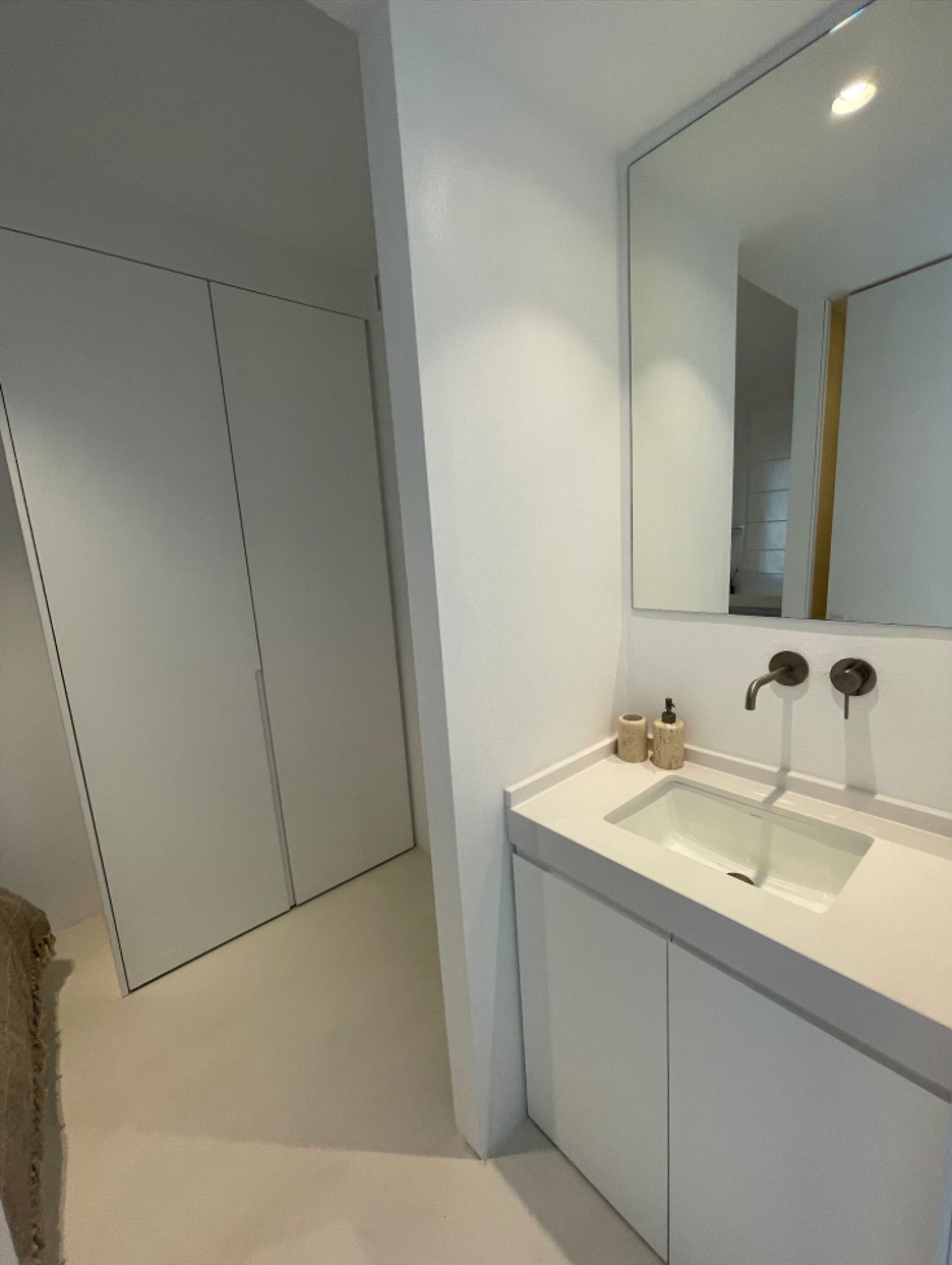 Un bagno moderno con un lavandino bianco, uno specchio e una porta.