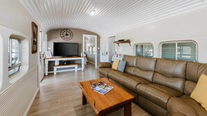A cozy living room with a brown leather sofa, a wooden coffee table, and a television on a white stand. - Red Rattler Retreat, Windeyer, Mudgee (Windeyer)
