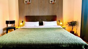 A hotel room with a large bed, two bedside tables, a chair, a potted plant, and a wooden headboard with vertical slats. - Hotel Bergen Zur Post by Rikas Hotels (Bergen)