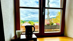 A window with a view of a house, a wooden bench, a white mug, and a black coffee maker on the window sill. - Hotel Bergen Zur Post by Rikas Hotels (Bergen)