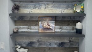 Een houten wandplank met decoratieve objecten en een lijst met foto.