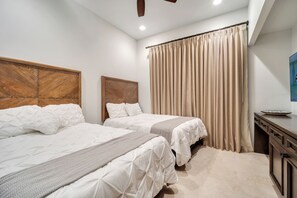 Une chambre d’hôtel avec deux lits, une tête de lit en bois, un rideau beige et une petite table avec un plateau.