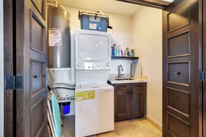 Een compacte keuken met een ingebouwde wasmachine en droger, een spoelbak en houten kastjes.