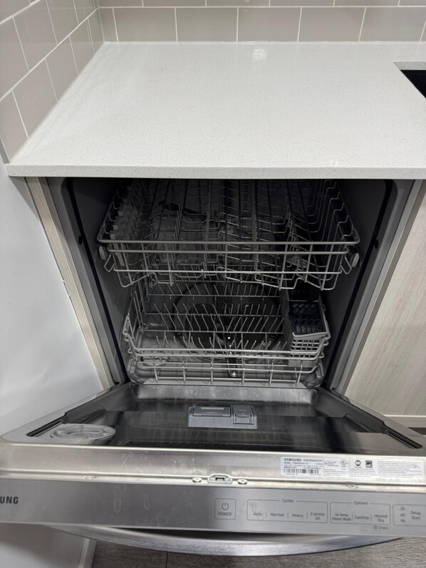 An empty dishwasher with a control panel displaying various settings and a label indicating it is a Samsung model.