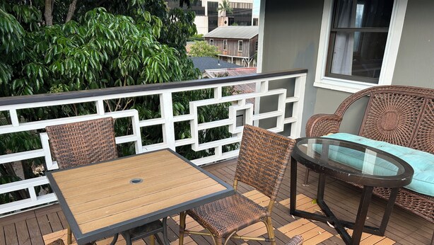 Eine Terrasse mit Korbmöbeln, darunter ein Tisch und Stühle, sowie ein Couchtisch mit Glasplatte.