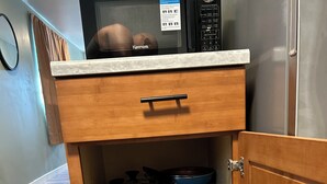 Eine Küche mit einer Mikrowelle auf der Arbeitsfläche, einem Holfläschchen mit einer Schublade und einem Edelstahl-Kühlschrank.