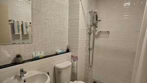 Ein modernes Badezimmer mit weißen Fliesen, einem Waschbecken, einer Toilette und einer Duschkabine.