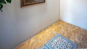 Ein Zimmer mit Marmorboden, einem gerahmten Gemälde, einer Wandleuchte und einer dekorativen Uhr.