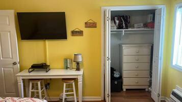 A bedroom with a bed, a desk, a chair, a television, a closet, and a door.