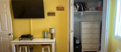 Een slaapkamer met een bed, een bureau, een stoel, een televisie, een kast en een deur.