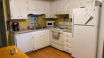 A kitchen with white cabinets, a microwave, a stove, and a refrigerator.