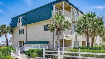 A two-story building with a balcony on the second floor, a green awning, and a sign indicating private property.