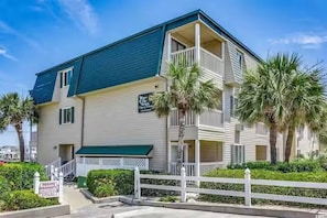 A two-story building with a balcony on the second floor, a green awning, and a sign indicating private property.