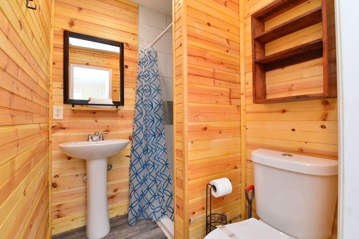 A wooden-paneled bathroom with a sink, toilet, and shower curtain.