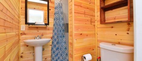 A wooden-paneled bathroom with a sink, toilet, and shower curtain.