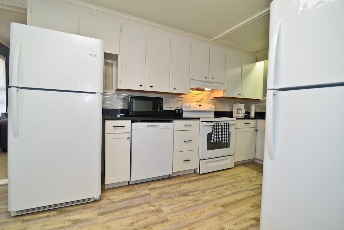 A kitchen with white cabinets, a microwave, a dishwasher, and a stove.
