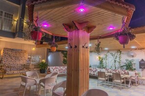 An outdoor patio area with wooden furniture, hanging plants, and a tiled floor. - Private villa with pool in Deadsea Jordan (Alshooneh Aljanobieh)