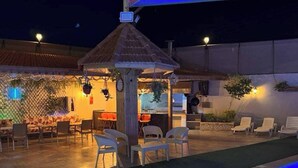 Un espace piscine extérieur doté d’un coin salon couvert et d’un petit kiosque.
