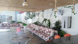 Un espace détente moderne comprenant un canapé, un ventilateur et des plantes décoratives.