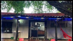 Un bâtiment avec une entrée carrelée, un portail grillagé et un hamac rouge.