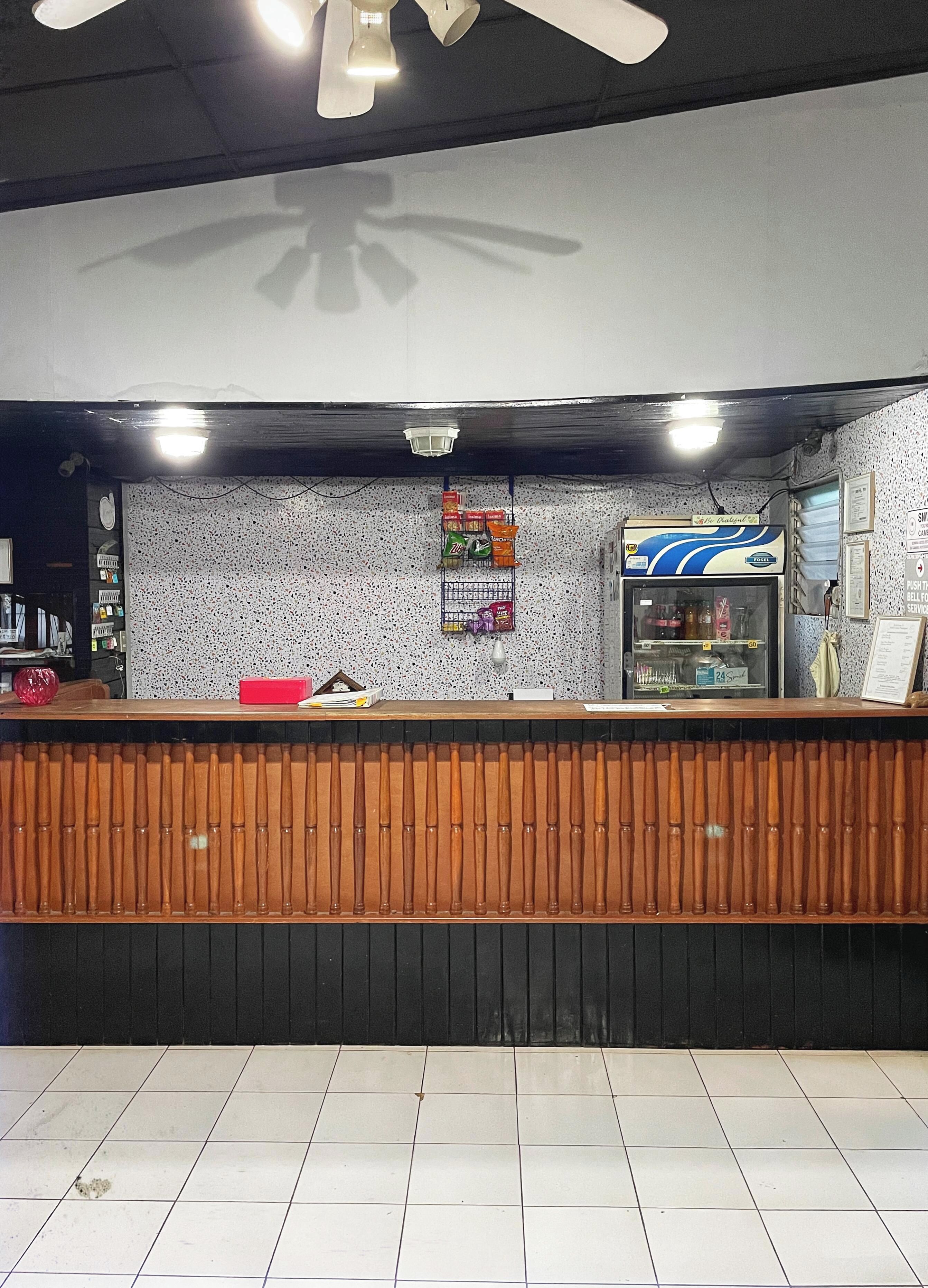 A reception area with a wooden counter, a vending machine, and a wall with various signs.