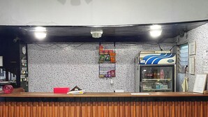 A reception area with a wooden counter, a vending machine, and a wall with various signs. - Oasis Hostel (Managua)