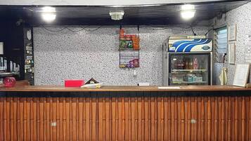 A reception area with a wooden counter, a vending machine, and a wall with various signs.