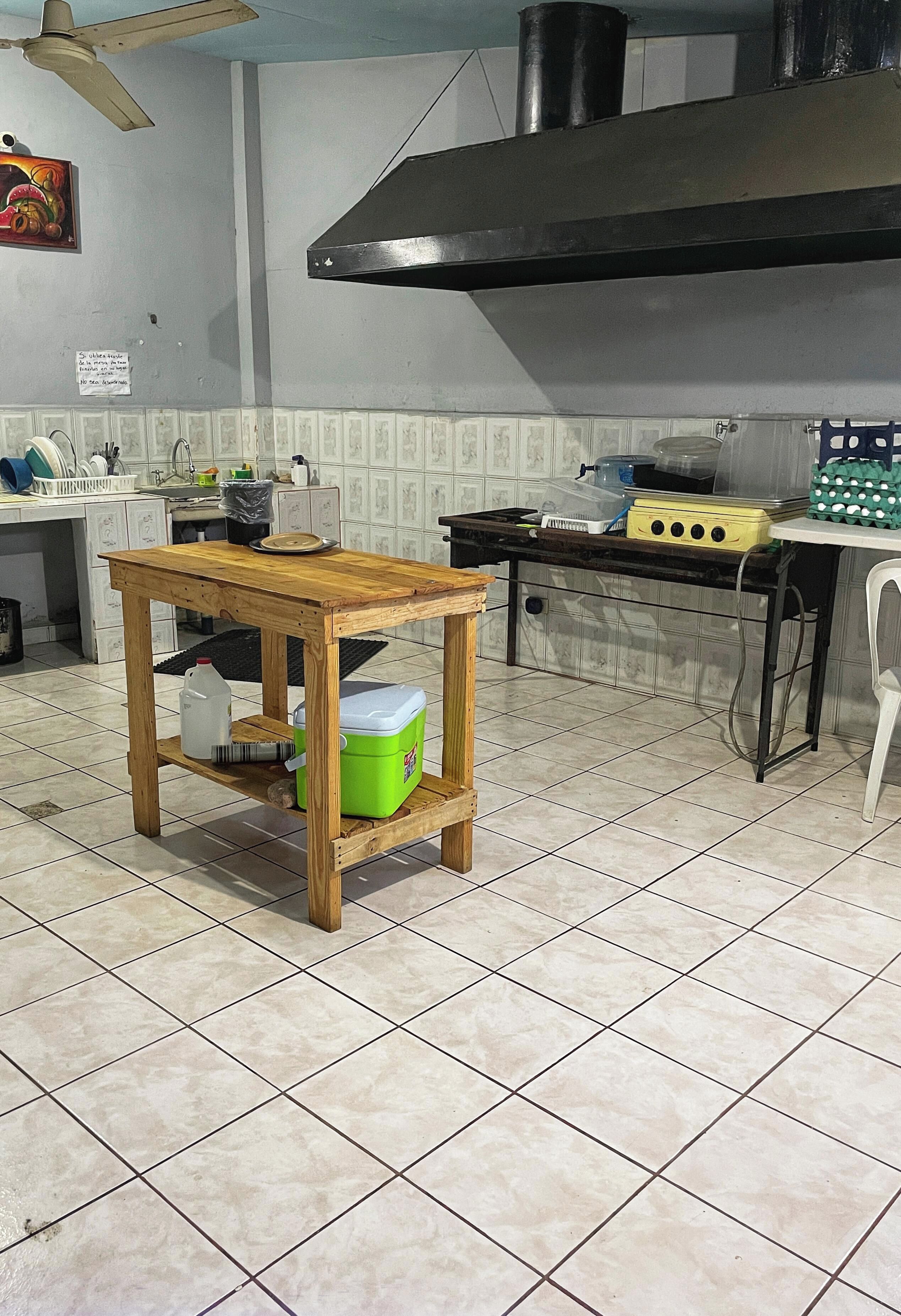 A kitchen with a wooden table, a green cooler, and a yellow appliance on the counter.