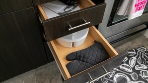 Un cajón de cocina con un agarrador negro acolchado y un recipiente de plástico blanco.