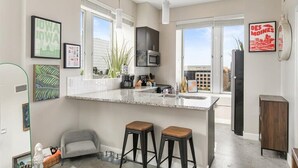 Una cocina moderna con una isla grande, taburetes de bar y vistas de la ciudad.