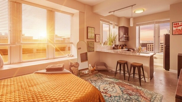 Un apartamento moderno con una cama grande, una cocina con barra y vistas a la ciudad.