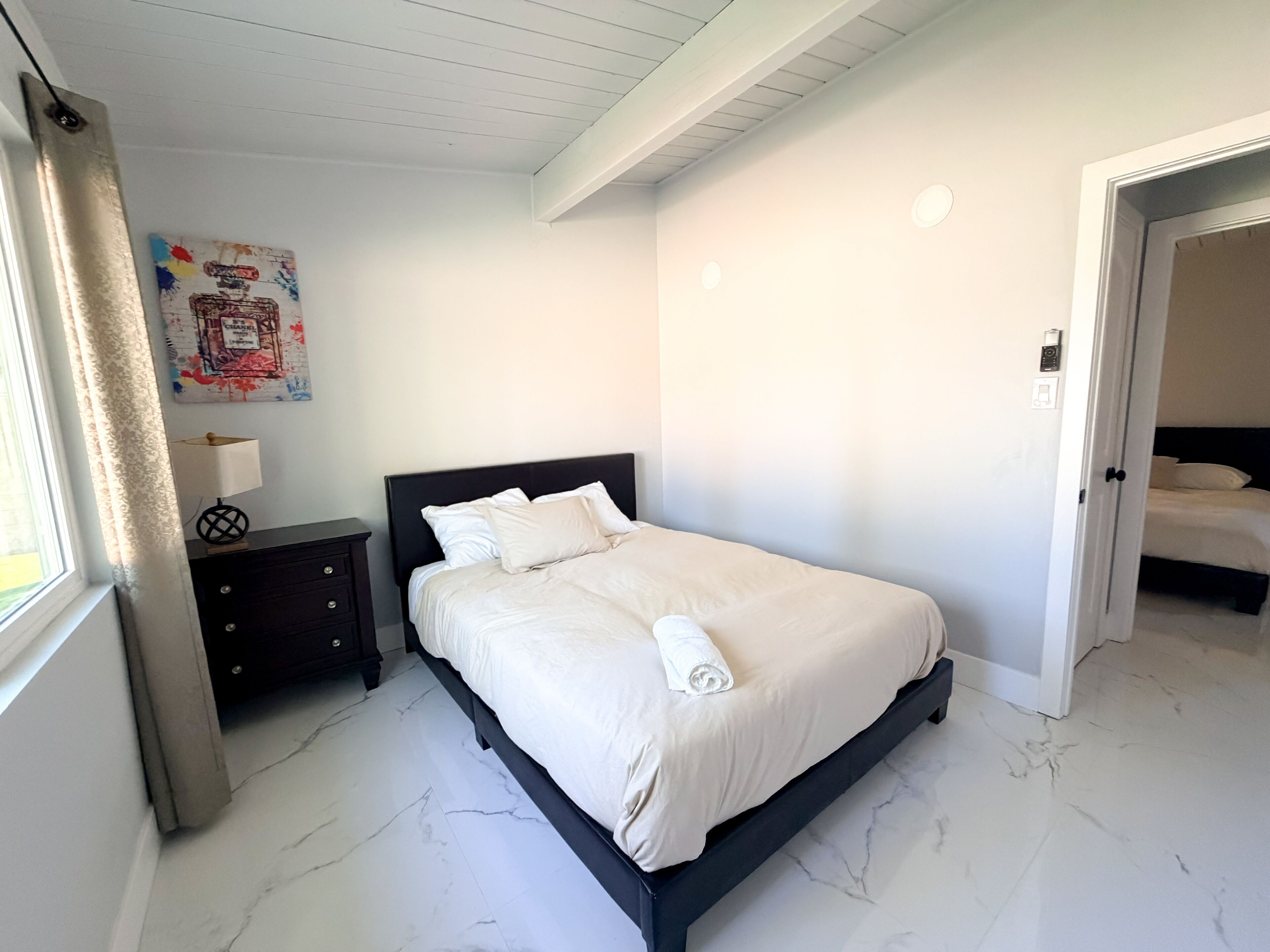 A bedroom with a bed, nightstand, and a wall-mounted painting.