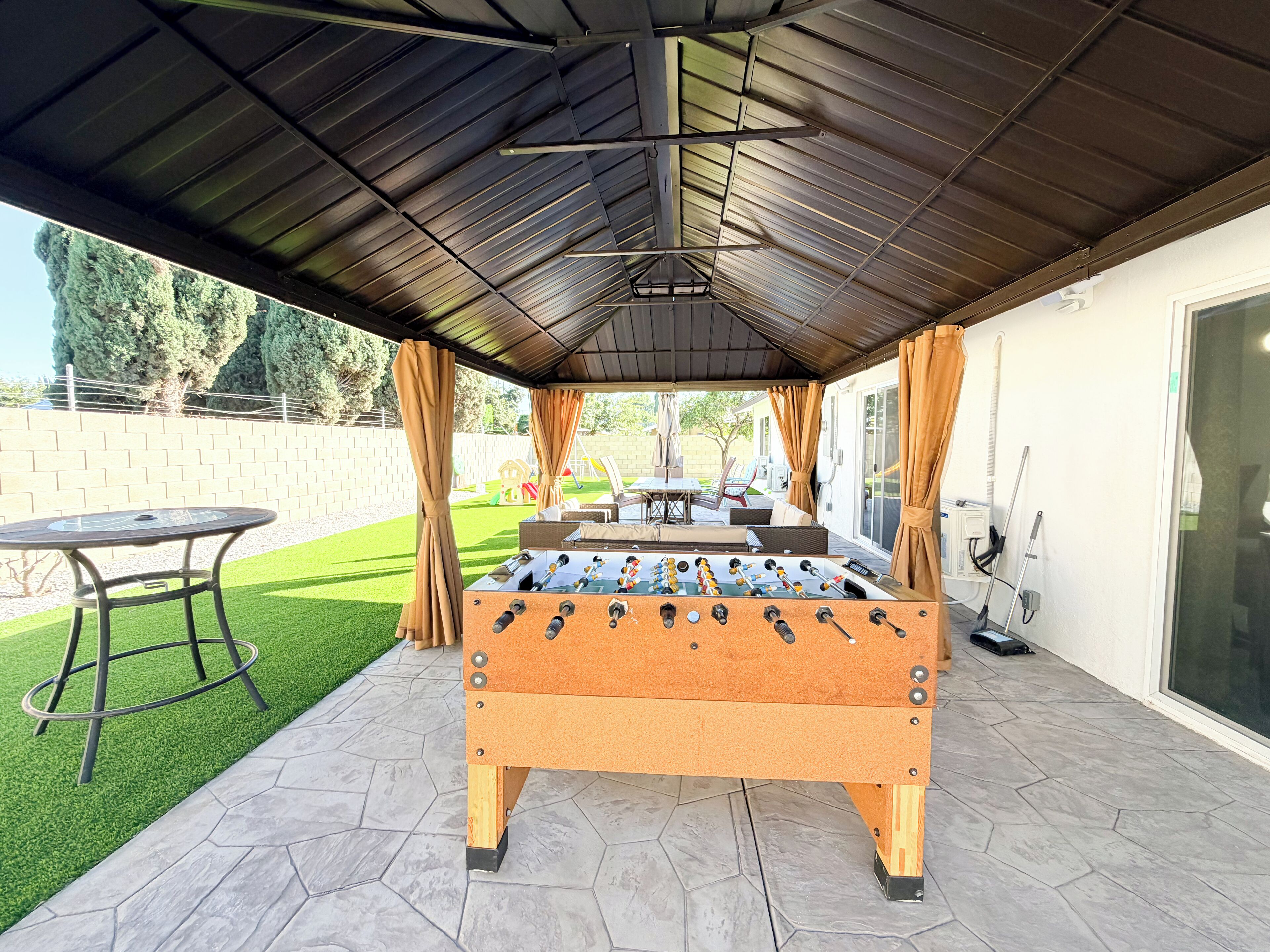 An outdoor patio area with a foosball table, a table, and chairs.