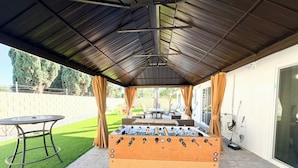 An outdoor patio area with a foosball table, a table, and chairs.