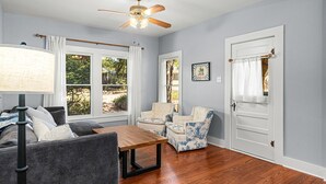 A room with a ceiling fan, a table, two chairs, a sofa, and a door. - Cherry Street Retreat - 1 Block from Main! (Bandera)