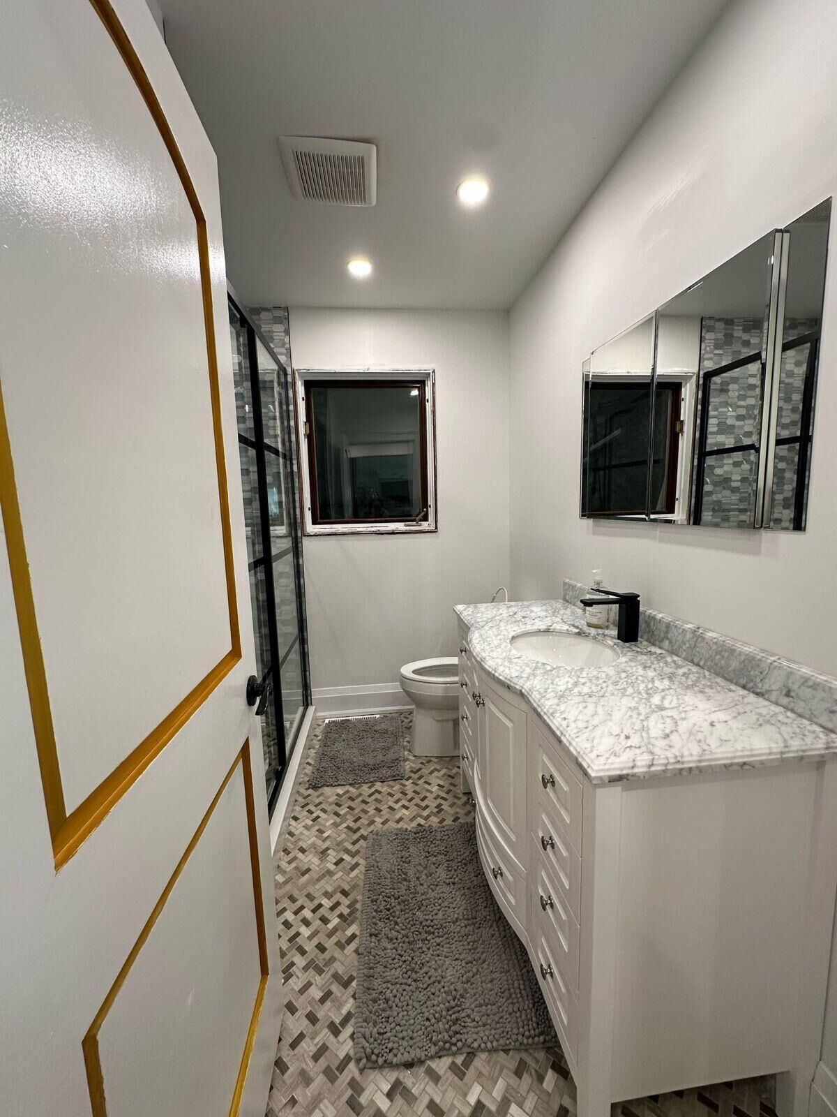 Un baño con tocador blanco, un espejo, inodoro y zona de ducha.