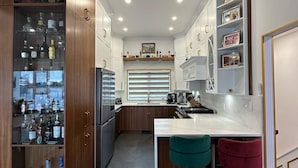 Een moderne keuken met houten kastjes, een geïntegreerde wijnkoeler en een centraal kookeiland met krukken.