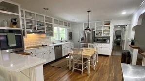 Une cuisine moderne avec des meubles blancs, des appareils en acier inoxydable et une table à manger en bois.