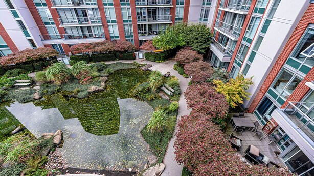 A courtyard with a pond, surrounded by buildings with red brick facades and large windows. - Downtown Vancouver Condo, Pool, Gym, Skytrain (Vancouver)